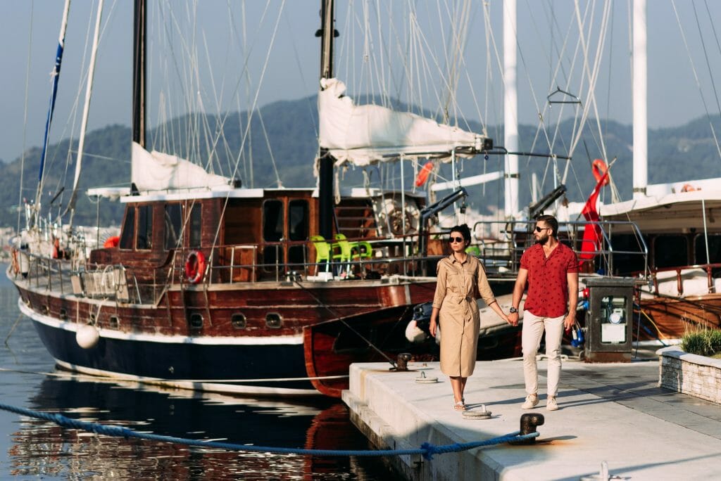 Man and woman near the yachts on the dock. Couple in love at the yacht